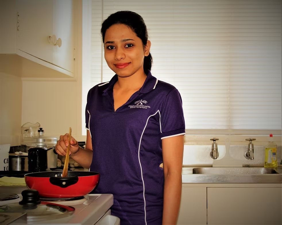 An Angels Homecare caregiver preparing a meal in a home kitchen